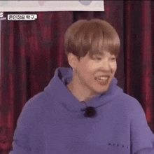 a close up of a person wearing a purple hoodie and making a funny face .