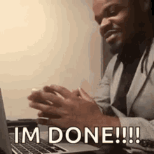 a man in a suit is sitting in front of a laptop computer and saying `` i 'm done ! ''