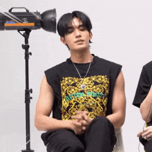 a man wearing a shirt that says never give up sits in front of a camera