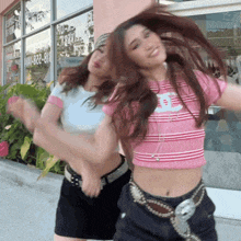 two girls are dancing in front of a store that has the number 818-222-8181 on the window