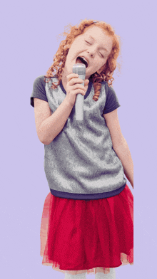 a little girl is singing into a microphone with the letter a in the corner