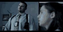 a man in a police uniform and tie is standing next to a woman in a dark room .