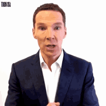 a man in a suit and white shirt is making a funny face and the words tookicka are behind him