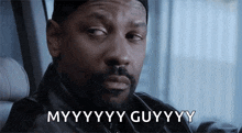 a man with a beard is sitting in a car and saying myyyyy guyyyy