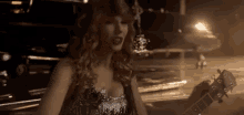 a woman in a sequined dress is playing a guitar in a dark room .