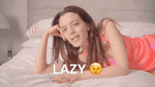 a woman in a pink dress is laying on a bed with the word lazy written above her