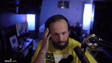 a man with a beard wearing headphones and a yellow shirt that says thescar36