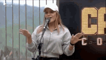 a woman is singing into a microphone while wearing a white hat .