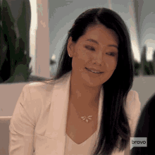 a woman wearing a white jacket and a necklace with the word bravo on it