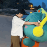 a man in a white shirt is hugging a stuffed animal with a yellow head