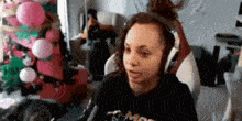 a woman wearing headphones is sitting in front of a christmas tree in a living room .