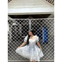 a woman in a white dress is standing in front of a white fence