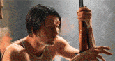 a man in a tank top is holding a rifle in his hands .