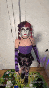a girl with purple hair and glasses is standing in front of a map that says haunted hills on it