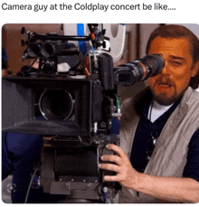 a man taking a picture with a camera with a caption that says camera guy at the coldplay concert be like