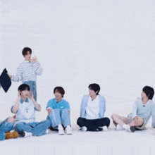 a group of young men are sitting on the floor with one holding a pillow