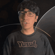 a man wearing glasses and a yusuf shirt