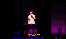 a man stands on a stage with a microphone in his hand and the words prove it behind him