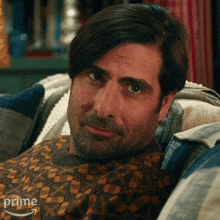 a man is sitting on a couch wearing a sweater with the word prime on it