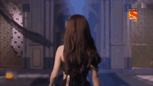 a woman in a black dress is walking in front of a door that says sony sab hd on it