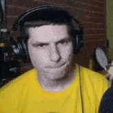 a man wearing headphones and a yellow shirt is making a funny face .