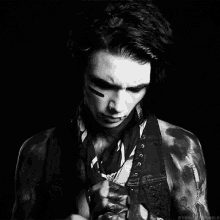 a black and white photo of a man with tattoos on his arms and face