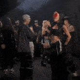 a group of people are dancing in a dark room with a woman wearing a mask