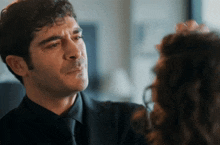 a man in a suit and tie is looking at a woman 's face