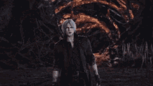 a man with gray hair and a black jacket stands in the dark