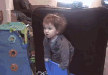 a little boy is standing in front of a blue playhouse