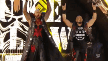 two wrestlers are standing on a stage with their arms in the air and one has a shirt that says anderson on it