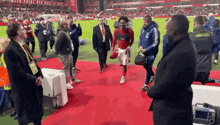 a soccer player is walking on a red carpet on a field .