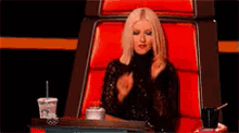 a woman is sitting in a red chair with a starbucks cup