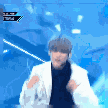 a man in a white jacket is dancing on a stage with a blue background