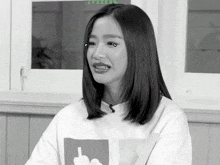 a black and white photo of a woman wearing a white sweater with a middle finger on it