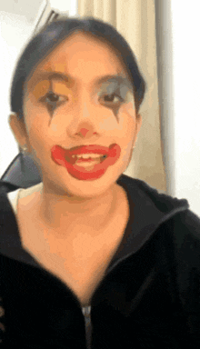 a woman with a clown face painted on her face is wearing a black jacket .
