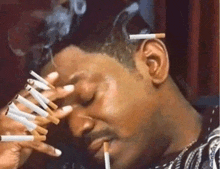 a man is smoking a lot of cigarettes and has a bunch of cigarettes sticking out of his ears .