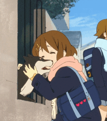 a girl with a blue bag with hearts on the straps is petting a dog