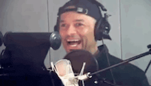 a man wearing headphones is smiling in front of a microphone .