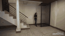 a woman stands in an empty room with the words made in animotica on the bottom right
