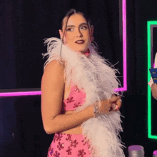 a woman in a pink dress with a white feather boa around her neck
