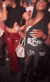 a woman in a black one shoulder top is dancing in a crowd of people