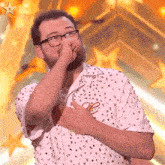 a man wearing glasses and a white shirt with sequins covering his mouth