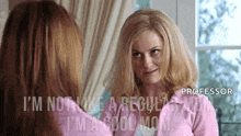a woman in a pink jacket is looking at herself in the mirror