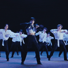 a group of men are dancing on a stage and one of them is wearing a crop top