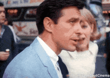 a man in a suit and tie stands next to a woman in a white dress