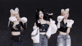three girls wearing cat ears and gloves are dancing