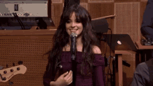 a woman in a purple dress is singing into a microphone in a room .