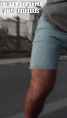 a man in shorts is walking down a street with the words estou a caminho meus queridos written above him