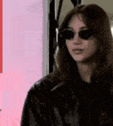 the woman is wearing sunglasses and a leather jacket .